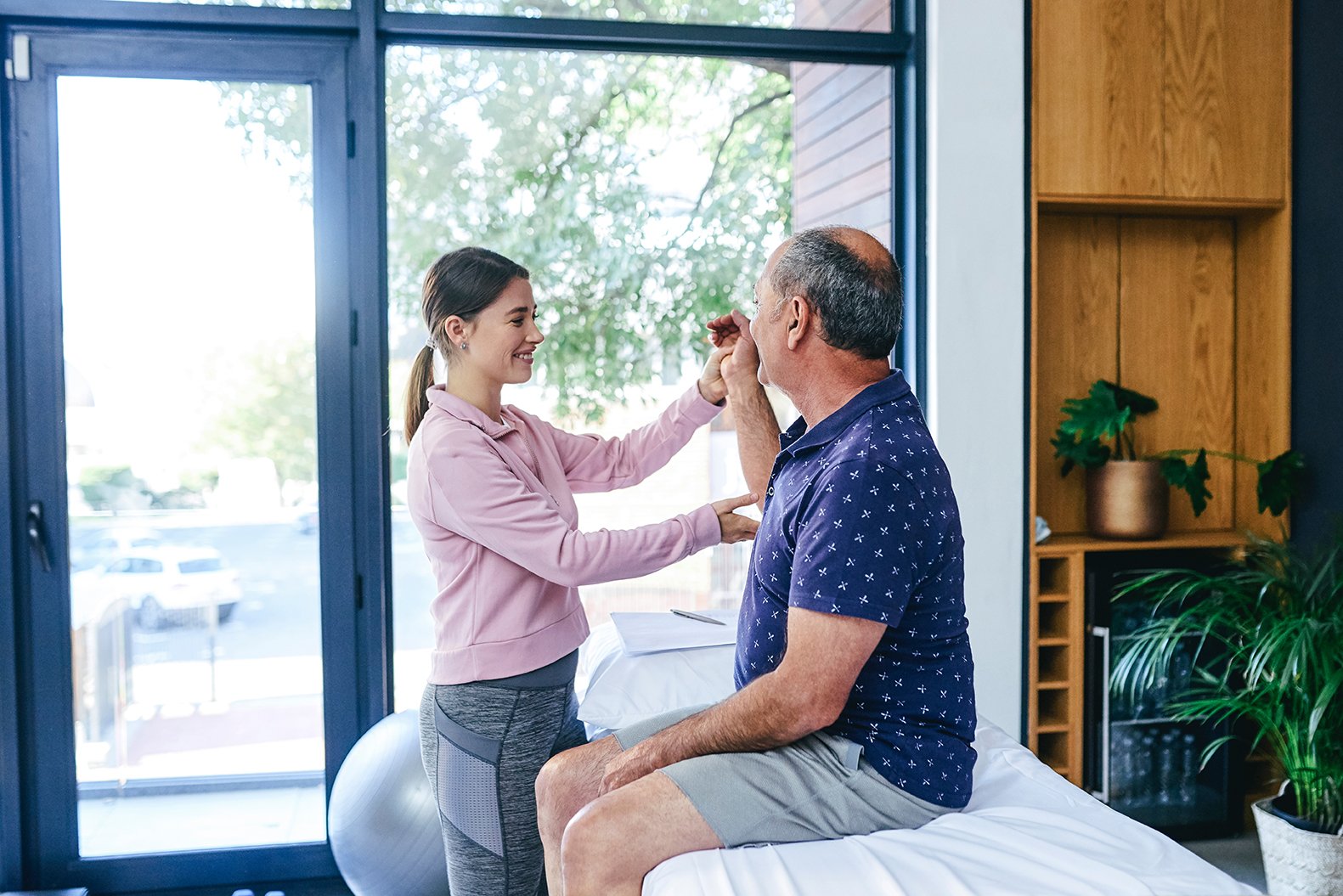 A woman assists an older gentleman with physiotherapy