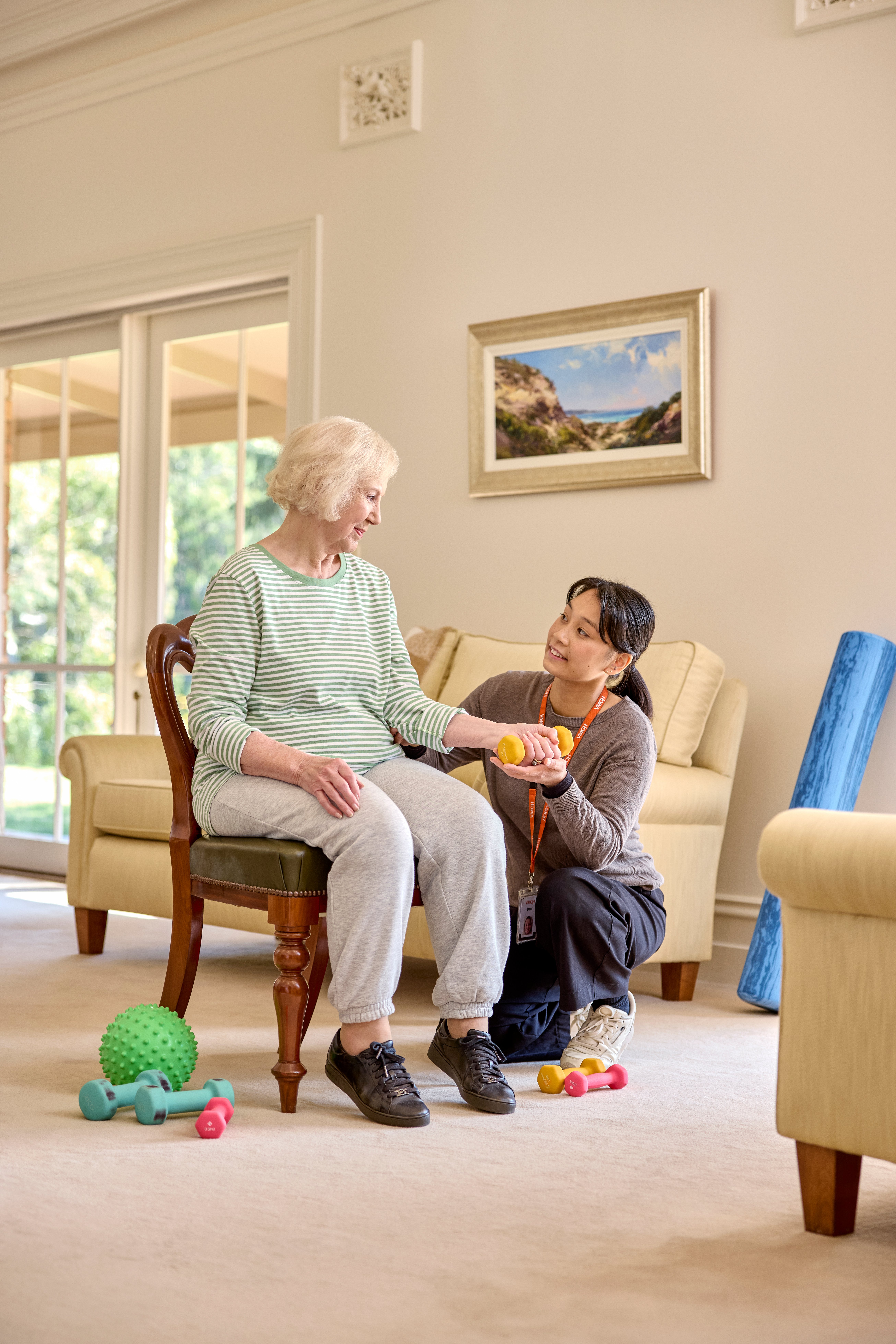Aged care worker assisting an elderly female resident to excerise