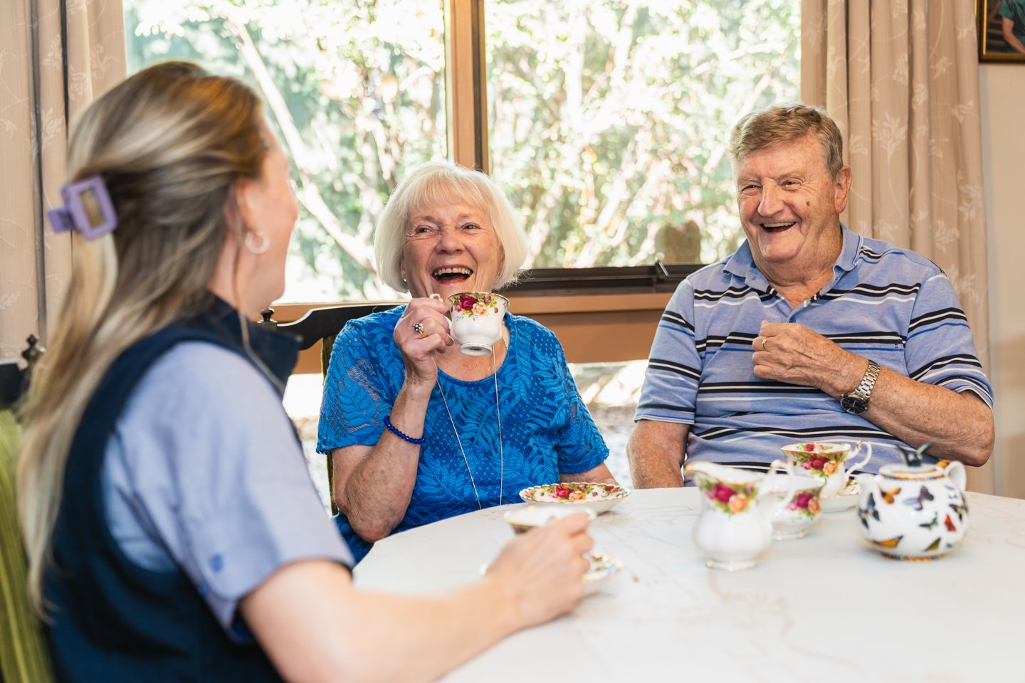 Aged care worker having a cup of tea with two elderly residents