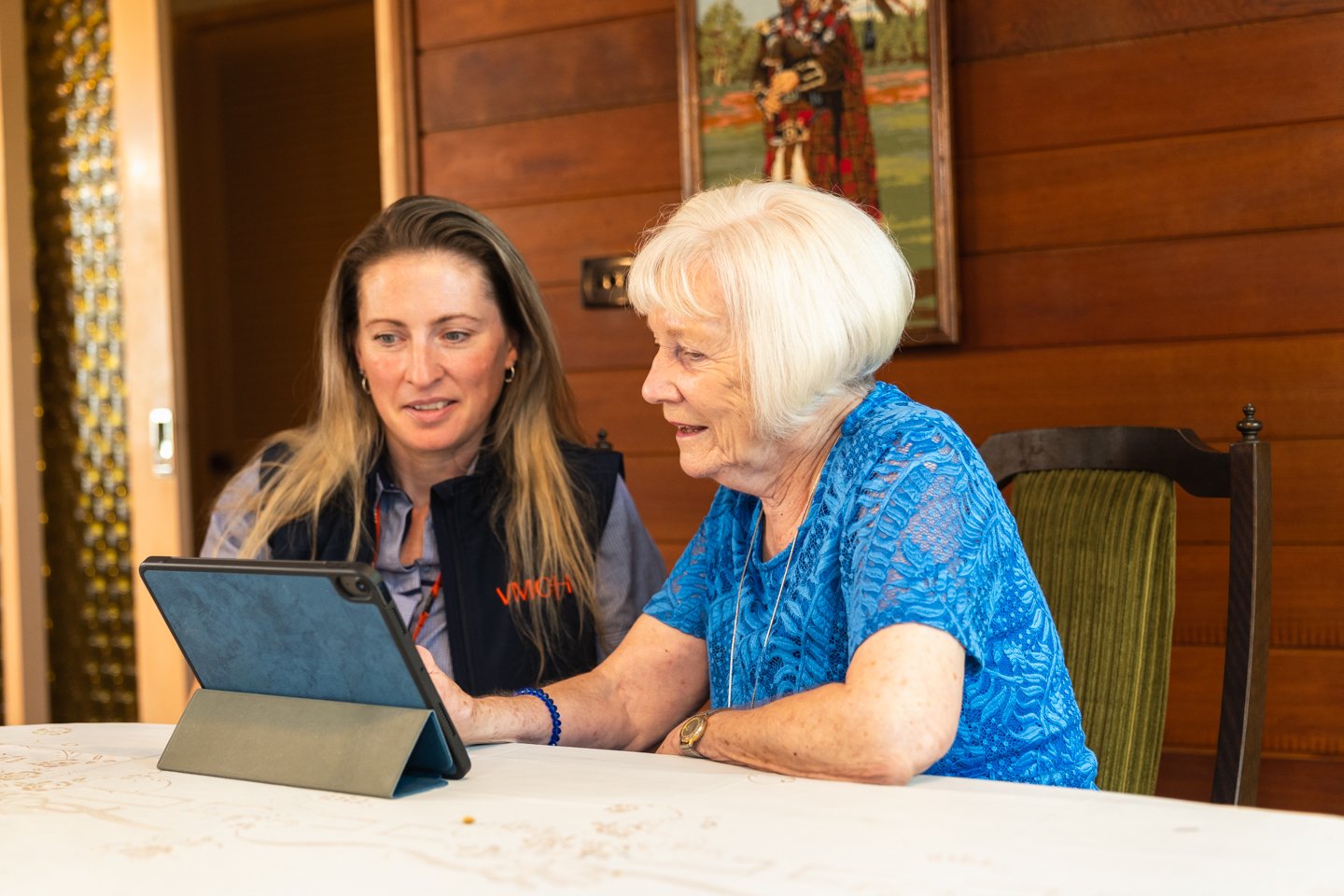 VMCH aged care resident using a tablet with support from a staff member, promoting digital inclusion and personalised care.