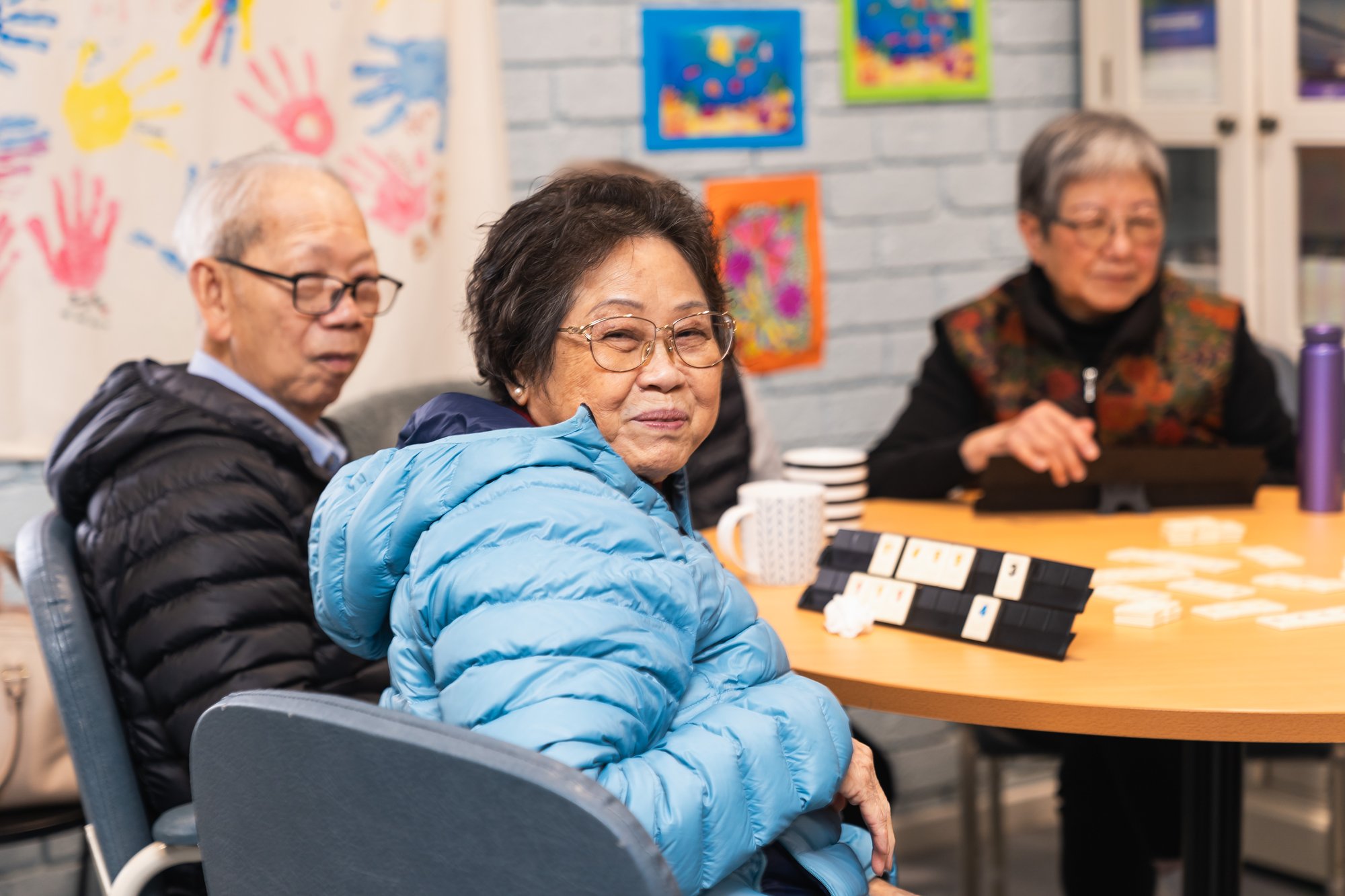 Three elderly Asian people sitting at a card table playing a game