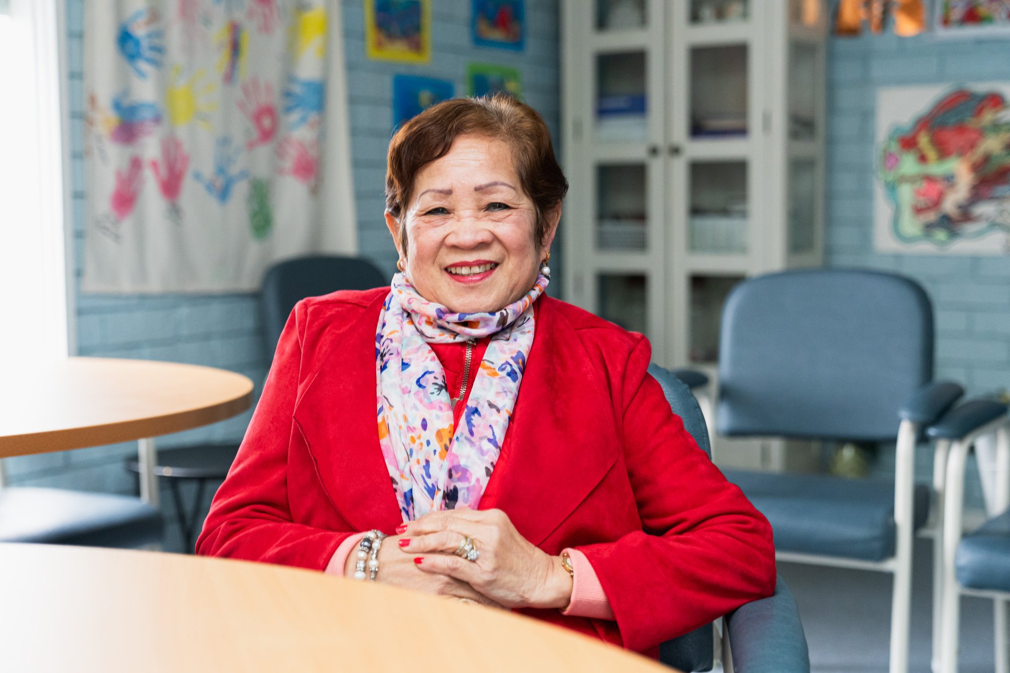 A woman wearing a red blazer sitting in a classroom.
