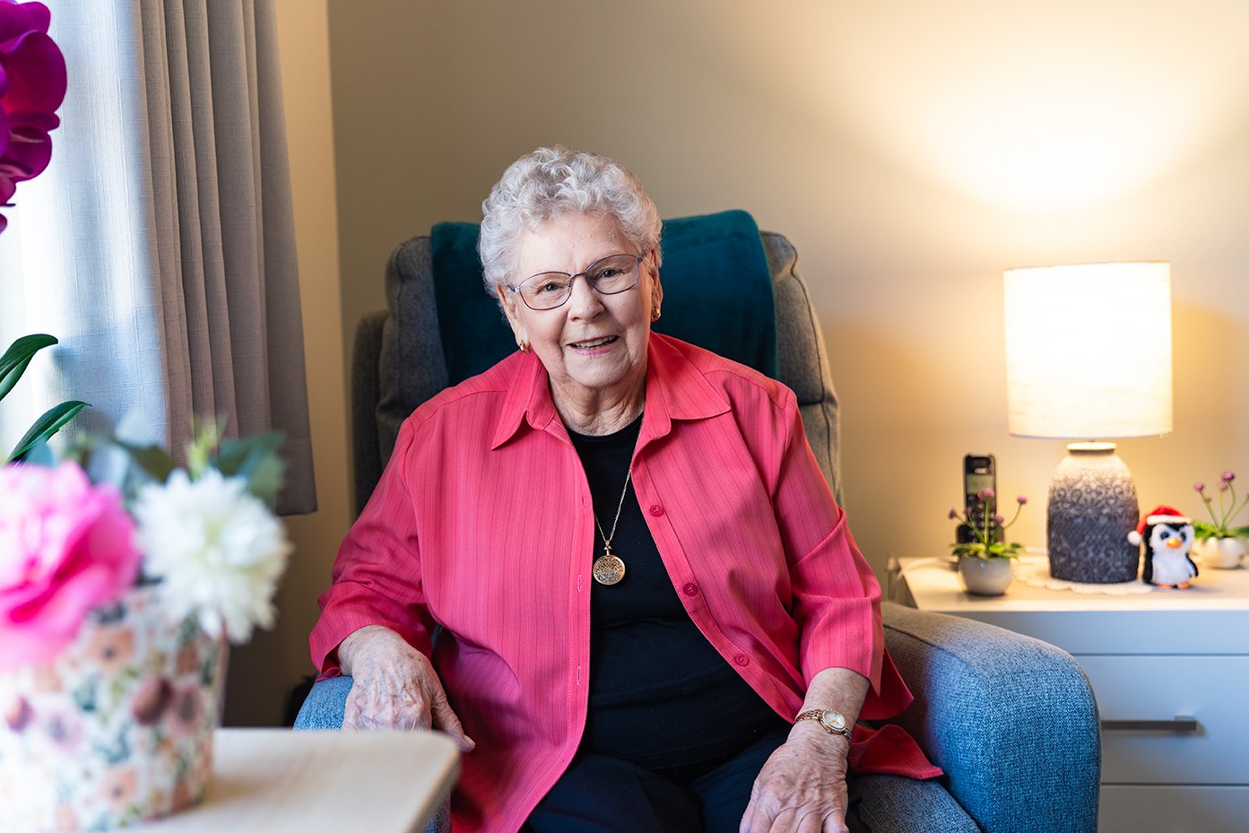 Elderly woman in pink shirt sitting in armchair