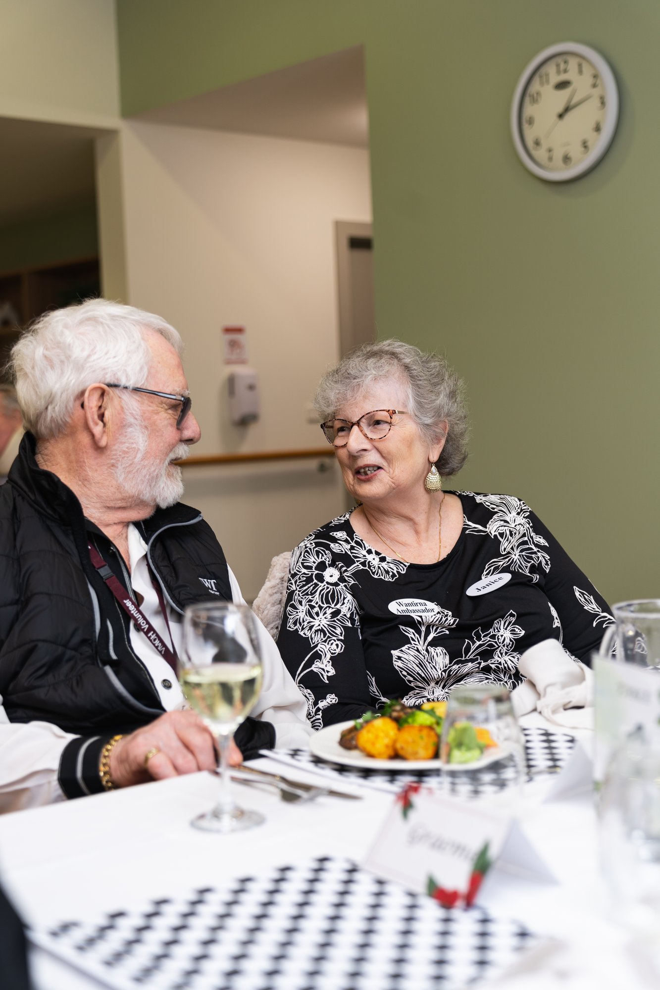 An elderly man and woman enjoying a glass of wine together