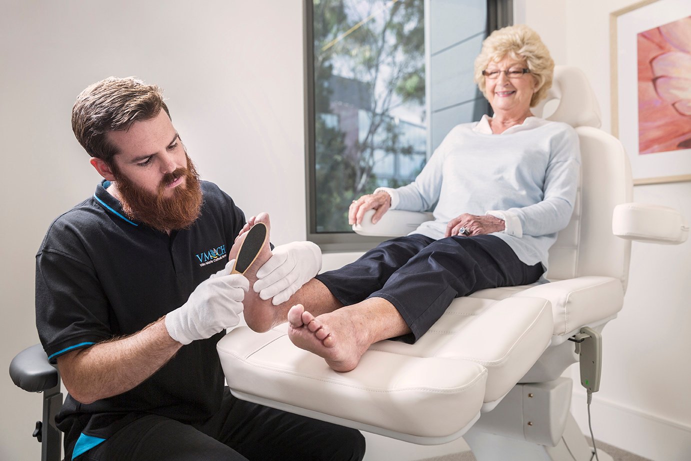 A man performs podiatry on an older lady
